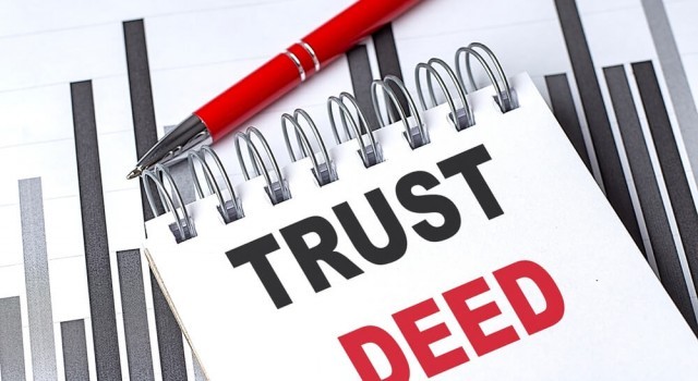 Trust deed concept with a notebook, red pen, and financial charts on white background . 