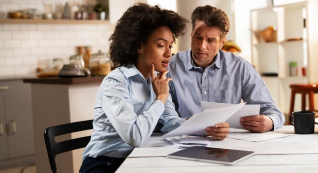 Young couple sitting in the kitchen preparing bills to pay