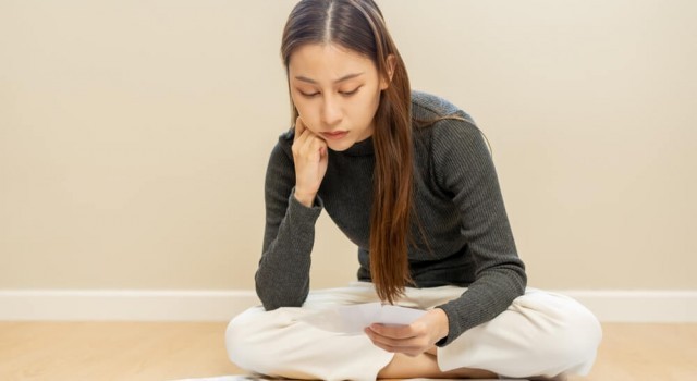 Sad woman sitting on the floor looking at debts